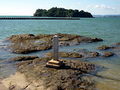 「天然記念物鳥巣半島ノ泥岩岩脈」と刻まれた石碑、沖に見えるのは神島